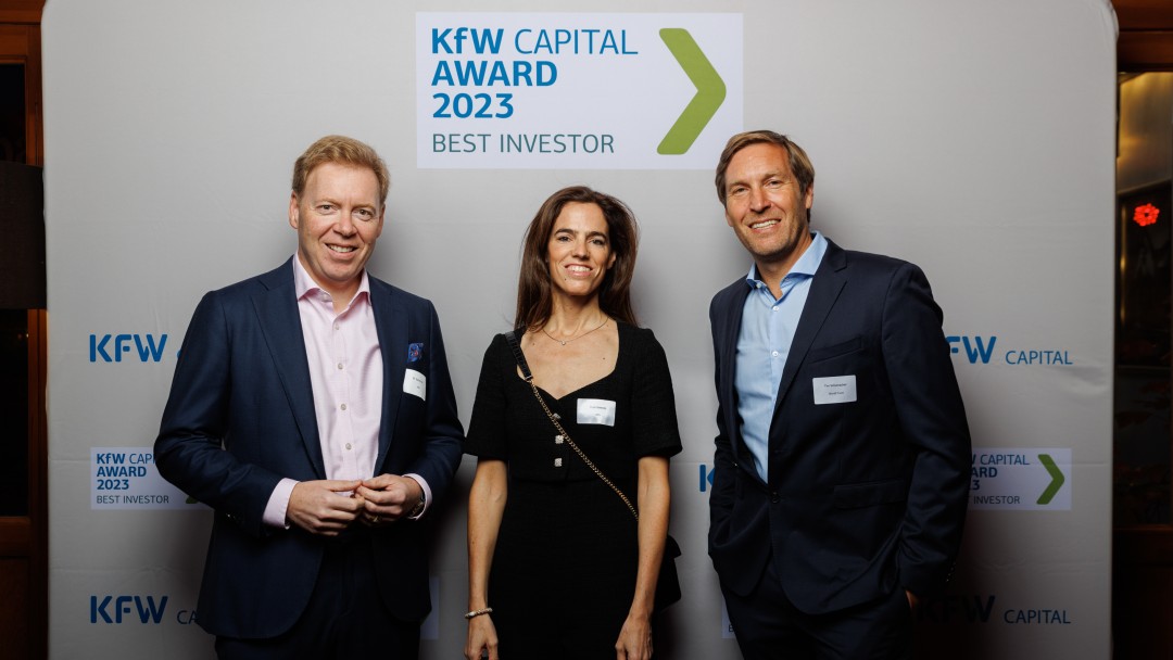 Drei Menschen vor der Fotowand des KfW Capital-Awards